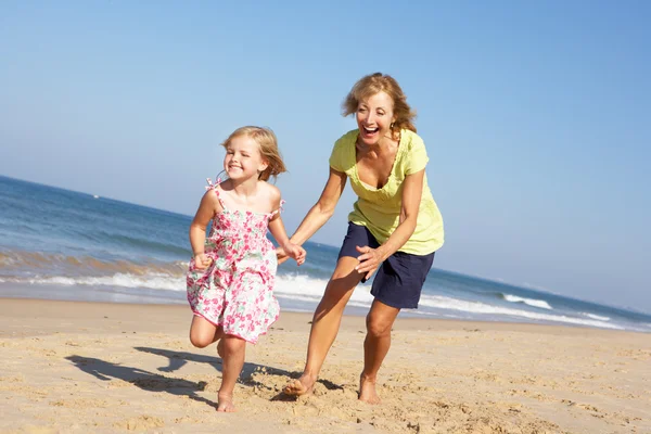 Großmutter und Enkelin laufen am Strand entlang — Stockfoto