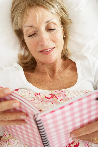 Mujer mayor Relajándose en la cama Diario de lectura — Foto de Stock