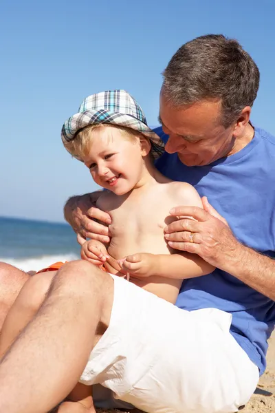 Grootvader en kleinzoon zittend op strand — Stockfoto