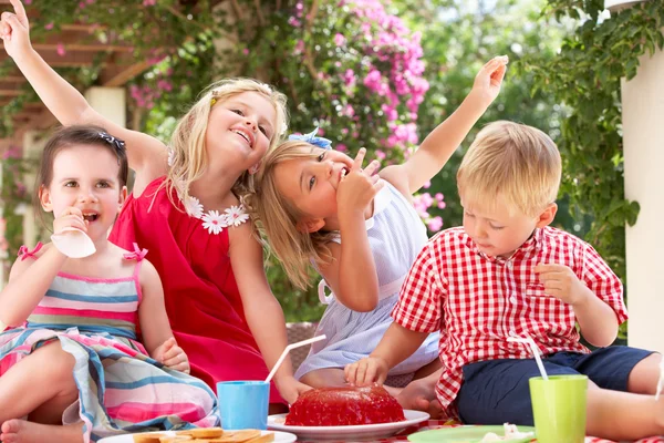 屋外のティー パーティーでゼリーを食べている子供のグループ — ストック写真