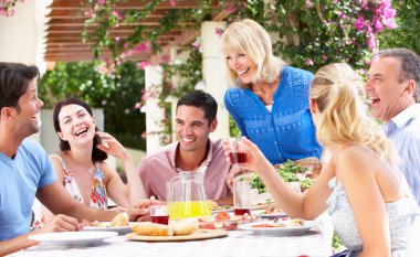 Group Of Young And Senior Couples Enjoying Family Meal clipart