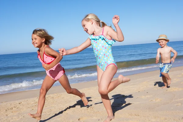 Drie kinderen lopen langs strand — Stockfoto