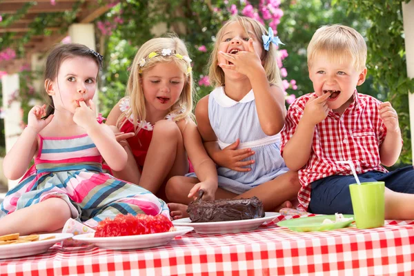 屋外のティー パーティーでゼリーとケーキを食べている子供のグループ — ストック写真