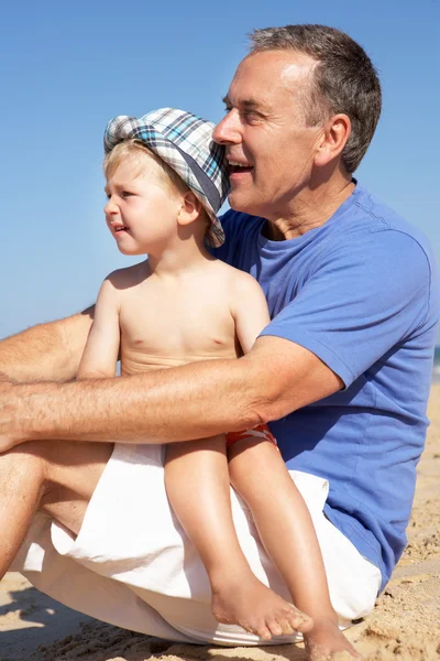 Farfar och sonson sitter på stranden — Stockfoto