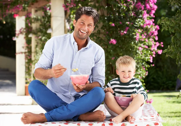 Otec a syn si pochutnávají snídaňové cereálie venku spolu — Stock fotografie
