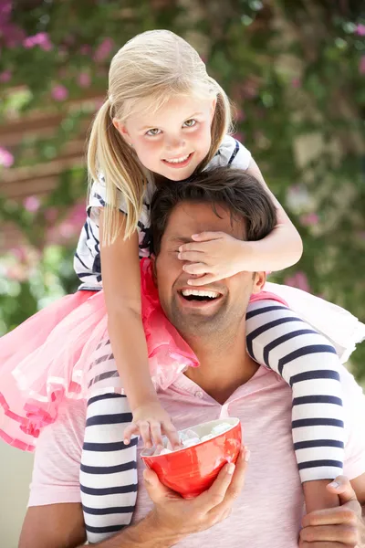 Pai dando passeio de filha em ombros ao ar livre enquanto come — Fotografia de Stock