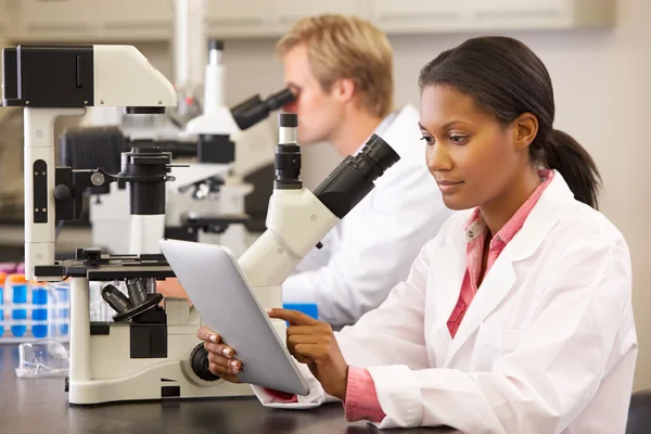 Cientistas usando microscópios e tablet digital em laboratório — Fotografia de Stock