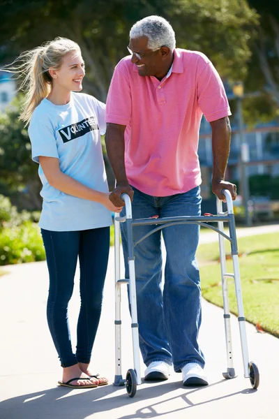 Teenage volontär hjälpa äldre man med promenader ram — Stockfoto