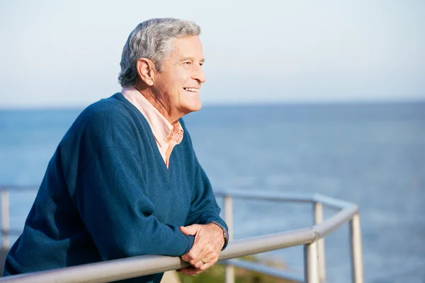 Senior schaut über Geländer aufs Meer — Stockfoto