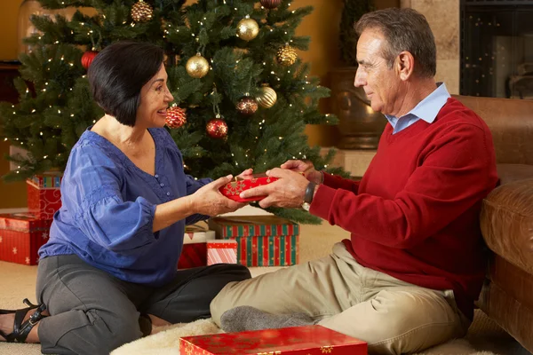 Couple âgé échangeant des cadeaux devant l'arbre de Noël — Photo