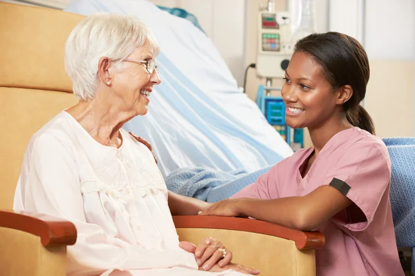 Enfermeira conversando com a paciente sênior sentada na cadeira pelo hospit — Fotografia de Stock