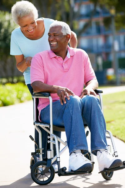 Anziana donna spingendo marito in sedia a rotelle — Foto Stock