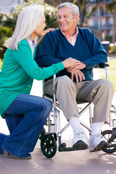 Anziana donna spingendo marito in sedia a rotelle — Foto Stock