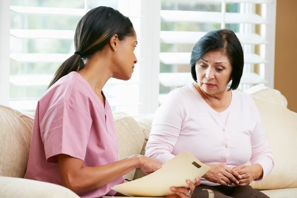 Krankenschwester bespricht Platten mit Seniorin zu Hause — Stockfoto