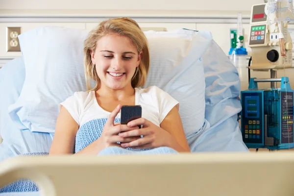 Adolescente Paciente feminina usando telefone celular na cama do hospital — Fotografia de Stock