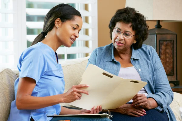 Krankenschwester bespricht Platten mit Seniorin zu Hause — Stockfoto