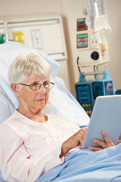 Старша жінка пацієнтка розслабляється в лікарняному ліжку з цифровим табло — стокове фото