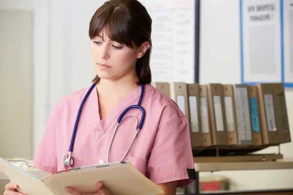 Sjuksköterska läsa patientens anteckningar på sjuksköterskor station — Stockfoto