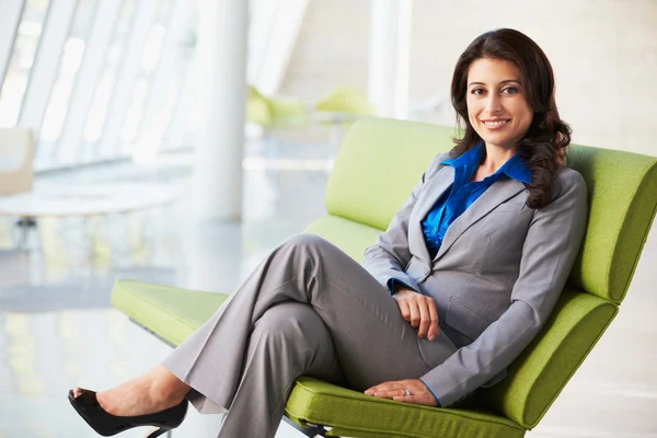 Retrato de una mujer de negocios sentada en un sofá en una oficina moderna —  Fotos de Stock