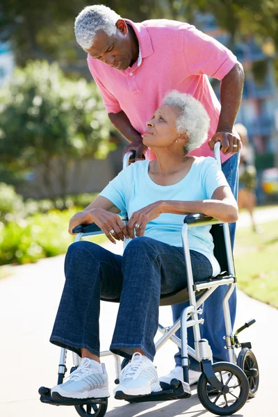 Старшая женщина толкает несчастного мужа в инвалидном кресле — стоковое фото