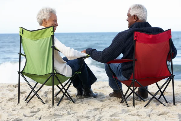 Pareja mayor sentada en la playa en tumbonas — Foto de Stock