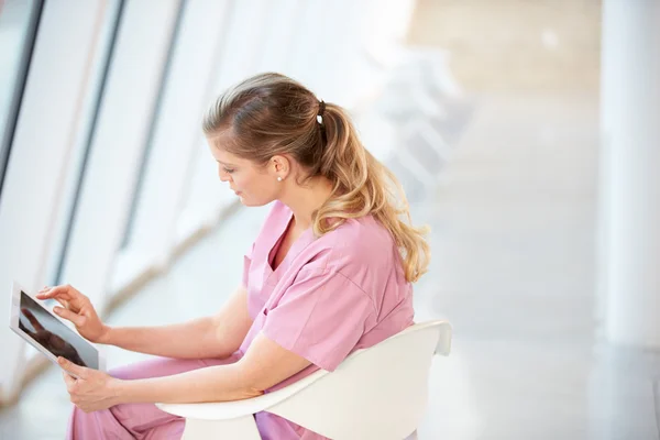 Infirmière féminine assise dans la chaise en utilisant une tablette numérique — Photo