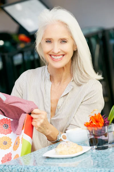 Senior vrouw snack in openlucht café genieten van na het winkelen — Stockfoto