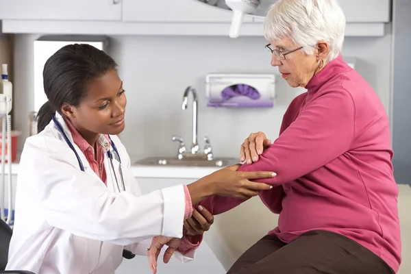 Läkare undersökande kvinnlig patient med armbågen smärta — Stockfoto
