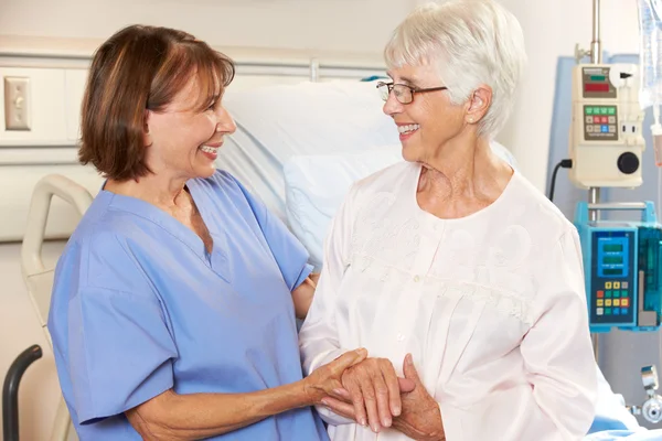 Enfermeira conversando com paciente do sexo feminino sênior na cama do hospital — Fotografia de Stock