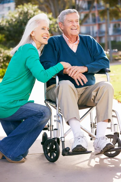 Anziana donna spingendo marito in sedia a rotelle — Foto Stock