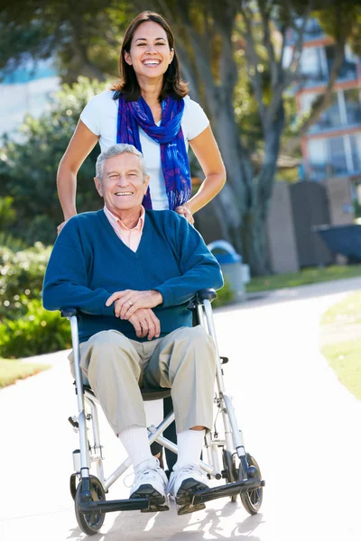 Volwassen dochter duwen senior vader in rolstoel — Stockfoto