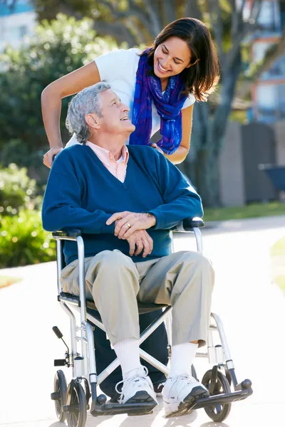 Hija adulta empujando padre mayor en silla de ruedas — Foto de Stock