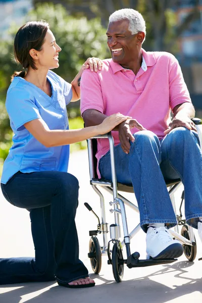 CARER trycka äldre man i rullstol — Stockfoto