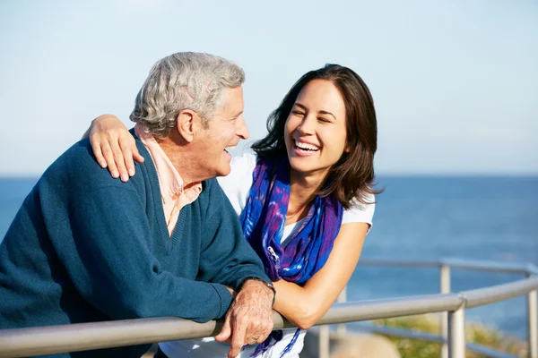 Senior mit erwachsener Tochter schaut über Geländer aufs Meer — Stockfoto