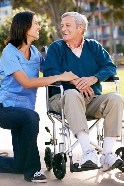 CARER trycka äldre man i rullstol — Stockfoto