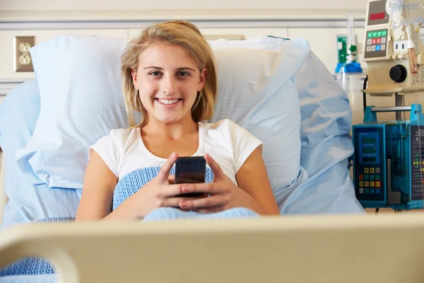 Adolescente Paciente feminina usando telefone celular na cama do hospital — Fotografia de Stock