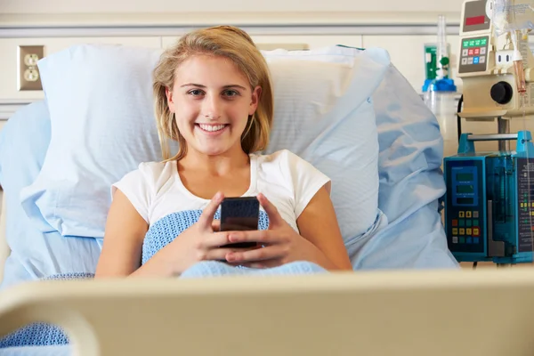 Patiente adolescente utilisant un téléphone portable dans un lit d'hôpital — Photo