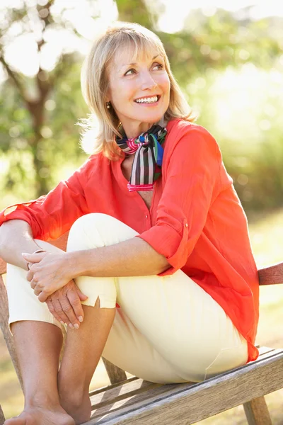 Senior Woman Sitting Outdoors On Bench Stock Picture