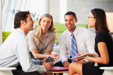 Businesspeople With Digital Tablet Having Meeting In Office clipart