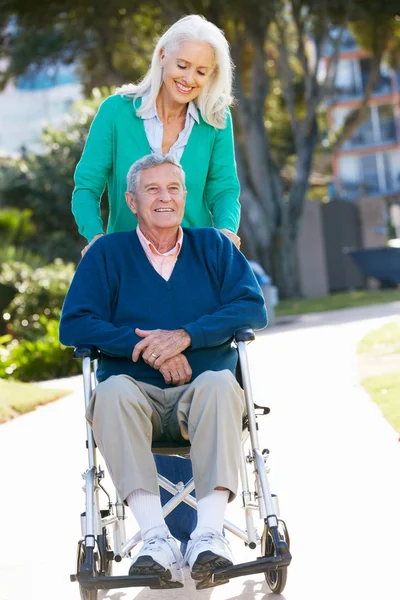 Старшая женщина толкает мужа в инвалидном кресле — стоковое фото