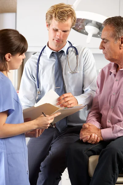 Manlig patient behandlas av läkare och praktikant — Stockfoto