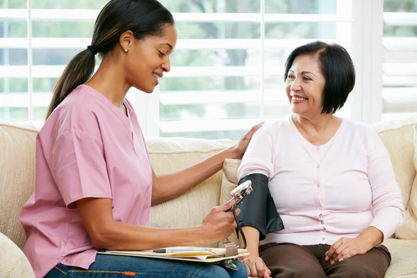 Sjuksköterska besöker äldre kvinnlig patient hemma — Stockfoto