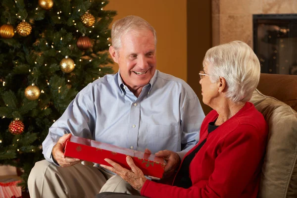 Couple âgé échangeant des cadeaux devant l'arbre de Noël — Photo