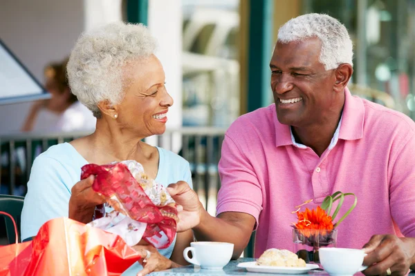 Старшая пара наслаждается закусками в открытом кафе после покупок — стоковое фото