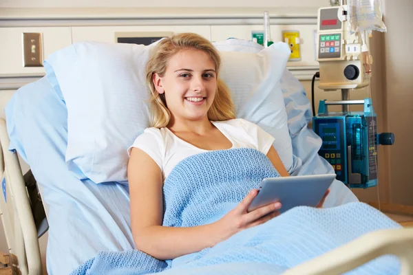 Paciente adolescente relaxando na cama do hospital com guia digital — Fotografia de Stock