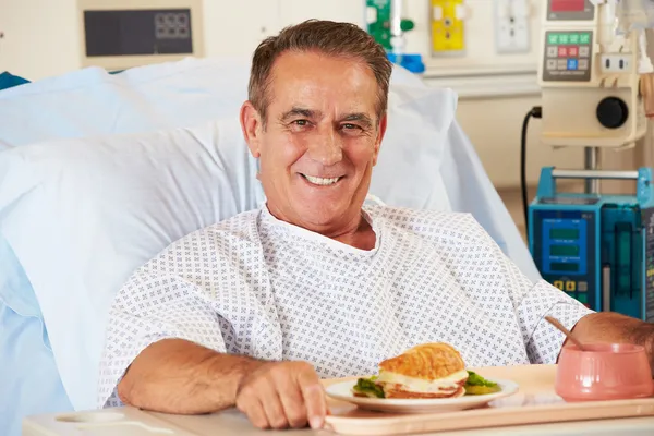 Мужской пациент наслаждается едой в больничной койке — стоковое фото