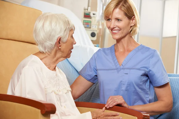 Verpleegkundige nemen naar senior vrouwelijke patiënt, zittend in een stoel door hospita — Stockfoto