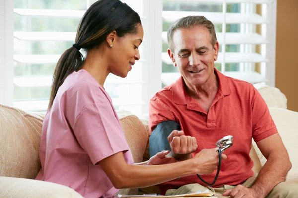 Verpleegkundige bezoekende senior mannelijke patiënt thuis — Stockfoto