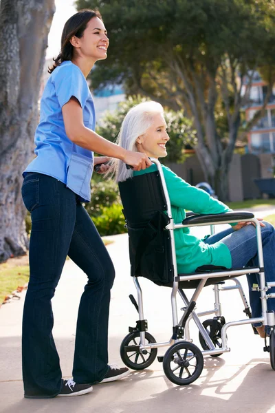 Aide Pousser une femme âgée en fauteuil roulant — Photo