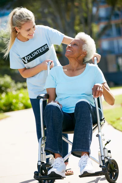 Teenage volontär driftigt senior kvinna i rullstol — Stockfoto